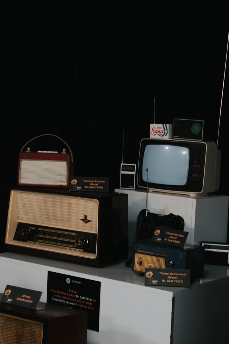 A collection of vintage radios and television sets on display, showcasing retro technology.