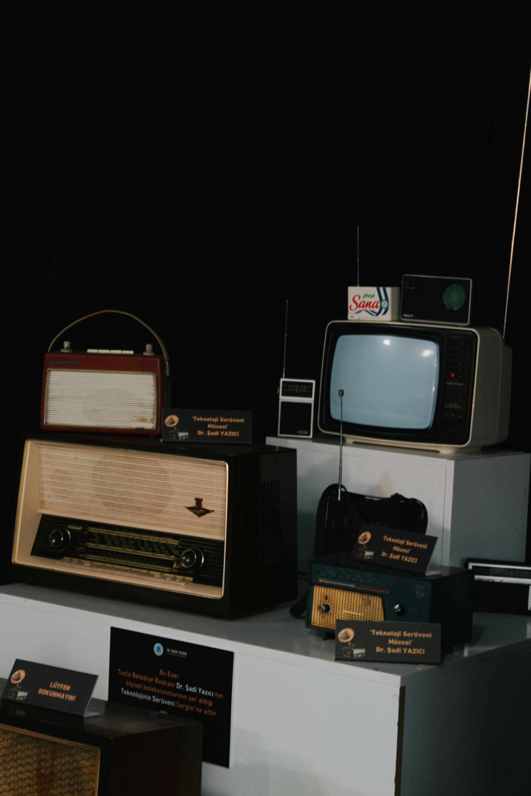 A collection of vintage radios and television sets on display, showcasing retro technology.